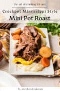 A serving of Mississippi style pot roast with carrots, potatoes, and peppers on mashed potatoes, displayed on a rectangular white plate.