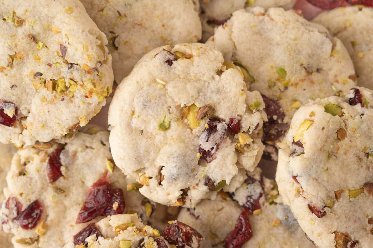A close-up view of crumbly cranberry cookies with visible pistachio pieces and dried cranberries.