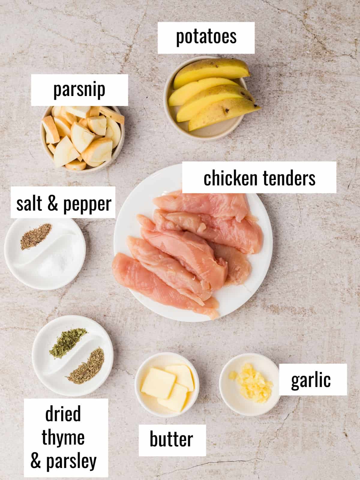 Ingredients displayed on a countertop: raw chicken tenders, sliced potatoes, parsnip pieces, minced garlic, butter, dried thyme and parsley, salt, and pepper.