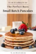 A stack of pancakes topped with blueberries, strawberries, and butter is displayed on a plate, with text promoting a small batch pancake recipe.