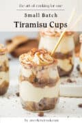 Three small glass jars filled with tiramisu, topped with whipped cream and cocoa powder, each with a spoon. Text reads Small Batch Tiramisu Cups and by aweekendcook.com.
