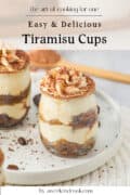 Two glass jars of layered tiramisu dessert topped with whipped cream and cocoa powder sit on a white plate, with cocoa scattered around. Text above reads: Easy & Delicious Tiramisu Cups.