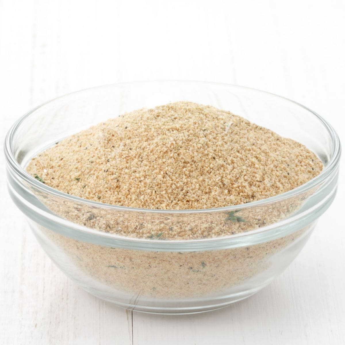 A clear glass bowl filled with light brown breadcrumbs sits on a white surface—an essential meatloaf binder featured in any guide to meatloaf.