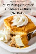 A slice of no-bake pumpkin spice cheesecake bar topped with whipped cream on a white plate, with a forkful taken out.