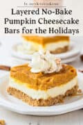 A slice of layered no-bake pumpkin cheesecake bar with whipped cream on top, served on a white plate.