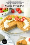 A maple syrup pie with a slice missing, topped with whipped cream and strawberries, sits on a table next to a glass of milk and whole strawberries.