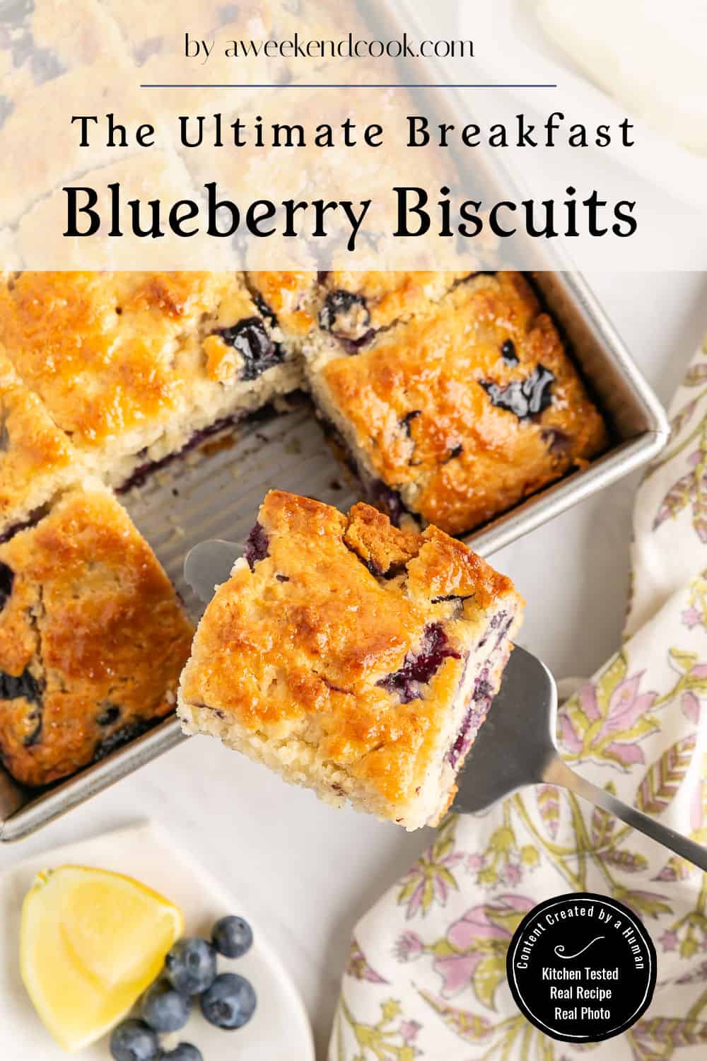 A tray of golden blueberry biscuits, one piece being lifted out, with fresh blueberries and a lemon wedge nearby on a patterned cloth. Text overlay reads The Ultimate Breakfast Blueberry Biscuits.