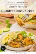 A bowl of cilantro lime chicken served on rice with lime slices and cilantro, with a fork holding a piece of chicken above the bowl.