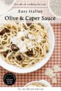 Plate of linguine topped with olives, capers, and shaved cheese sits on a checkered tablecloth, with extra cheese and a bowl of capers nearby. Text overlay describes an olive and caper sauce recipe.