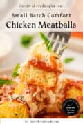 A fork holds a small batch chicken meatball topped with tomato sauce and herbs above a plate of similar meatballs garnished with grated cheese and basil.