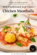 Three juicy chicken meatballs, made from a small batch meatball recipe, are topped with tomato sauce, grated cheese, and fresh basil leaves on a plate. A fork cuts into one tender chicken meatball, while a side of creamy ricotta cheese sits invitingly in the background.