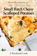 A spoonful of cheesy scalloped potatoes is held above a baking dish, topped with pepper and parsley, with text promoting a small batch recipe.