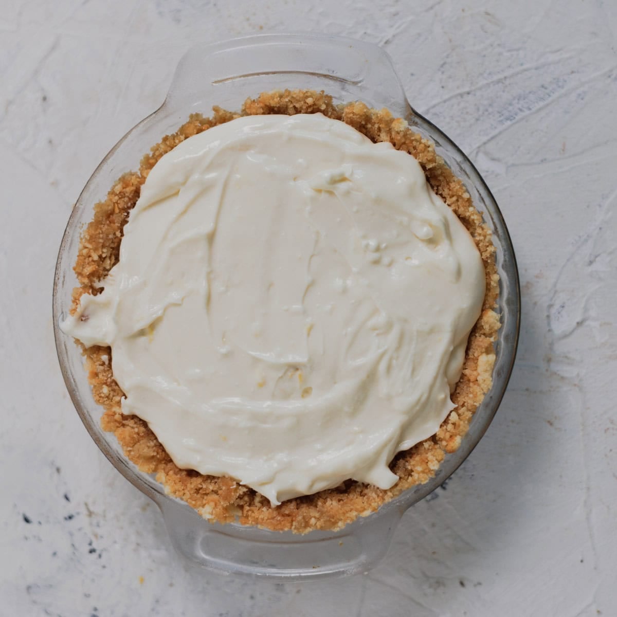 A pie crust in a glass dish filled with white cream filling.